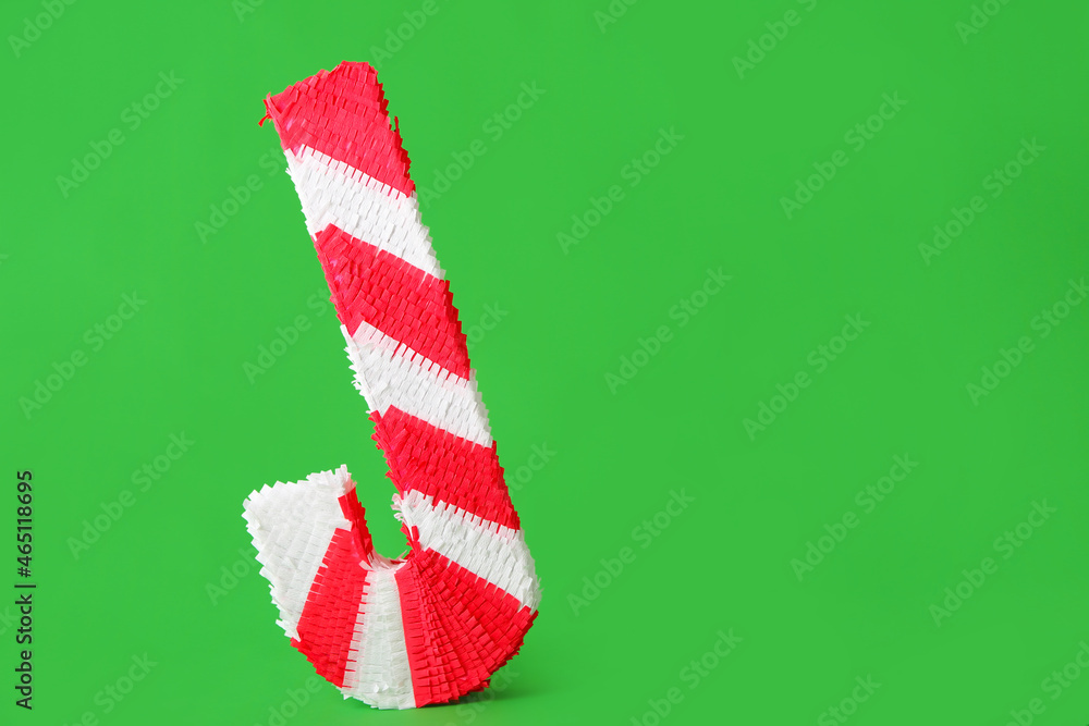 Mexican pinata in shape of cane on green background