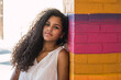 Portrait of a teenage Cuban girl leaning against a colorful wall, cuban latin teenager woman