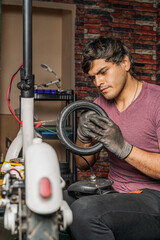 Wall Mural - Mechanic repairing an electric scooter sitting on chair holding the tire