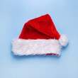 © Настя ВольФ - Red Santa Claus hat on a blue solid background. Christmas preparations. Isolated, top view.
