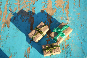 Wall Mural - Three, 3 wrapped vintage gift boxes with olive silk ribbon bow on blue (turquoise) old wooden background. Present box in craft paper with green bow with shadow. Holiday concept. Close-up. Top view