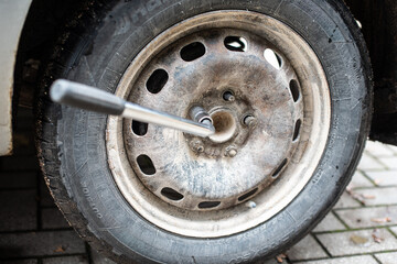 Wall Mural - The nut of the used car wheel is screwed out with a wrench.