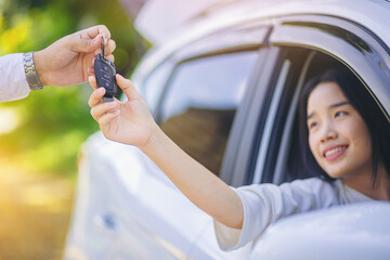 Young asian woman taking car key, keyless stystem for start car engine. Selected focus