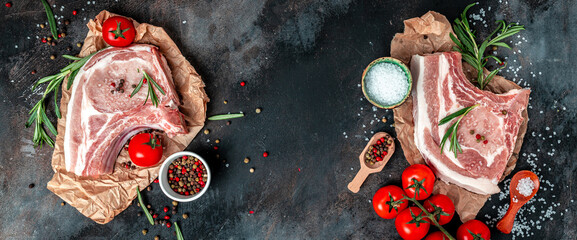 Organic Pork meat chop set with spices and rosemary and red pepper on black table. Long banner format. top view