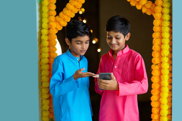 Wall Mural - Indian little boys using smartphone and enjoying diwali festival.