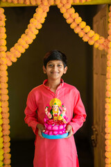 Wall Mural - Cute Indian little boy holding goddess laxmi sclupture in hand and celebrate diwali festival.