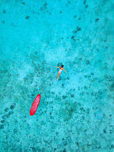 Woman With Surfboard Swimming In Blue Ocean At Huraa Island, Maldives