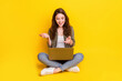 Full size photo of charming positive lady sit hold laptop on legs speak isolated on yellow color background