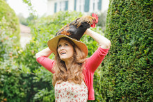 Mature Woman Carrying Rooster On Head In Backyard
