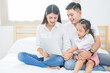 © sutthinon602 - Happy asian family people leisure in bedroom together. Father and mother with daughter relaxing and using laptop computer on bed