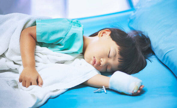 Fototapete - Sick asian little child boys hand who have saline intravenous (iv) drip bandage is sleeping on bed in the hospital
