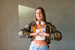 © Westend61 - Happy teenage girl gesturing heart shape in front of wall