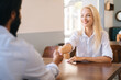 Close-up view from back of unrecognizable bearded business man handshaking with cheerful attractive young woman closing deal at business meeting, job interview, agreement business, selective focus.