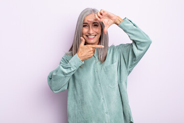 Wall Mural - middle age gray hair woman feeling happy, friendly and positive, smiling and making a portrait or photo frame with hands