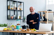 © Westend61 - Man with arms crossed standing at kitchen counter