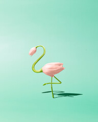 Contemporary art still life concept. Flamingo made from pink tulip flowers. Spring and summer green background. Flamingos Lover