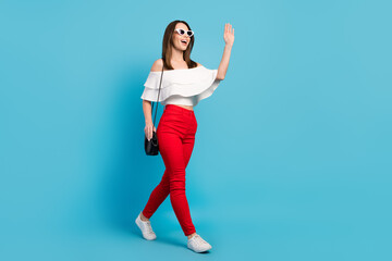 Wall Mural - Full body photo of funny brunette millennial lady go wave wear spectacles white top jeans isolated on blue color background