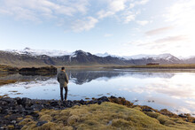 Anonymous Male Traveler Admiring Mountainous Lake Against Blue Sky