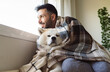 © Westend61 - Smiling man with dog looking through window during winter at home