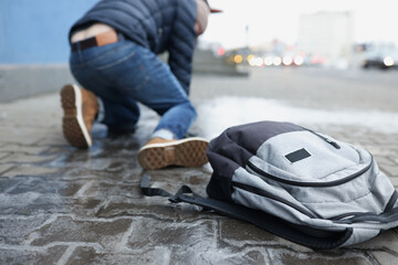 Backpack lying on slippery paving slabs near falling man closeup