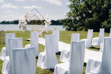 Wall Mural - Decorated wedding arch in nature.Wedding ceremony with an arch decorated with retro-style feathers on a lake background