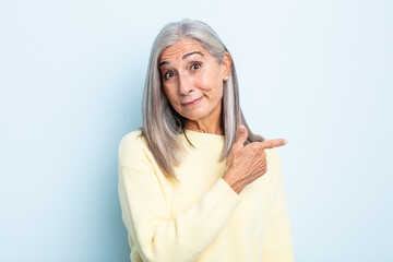 Wall Mural - middle age gray hair woman smiling cheerfully, feeling happy and pointing to the side and upwards, showing object in copy space