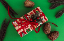 Christmas Or New Year Gift Box With Red Bow And Pine Cones On The Green Background