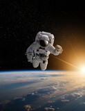 Fototapeta Kosmos - Astronaut in outer space over the planet Earth.Stars provide the background.erforming a space above planet Earth.Sunrise,sunset.Our home. ISS.Elements of this Image Furnished by NASA.