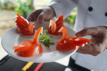 Close-up Of A Carved Tomato Salad Plate Holding By A Chef.