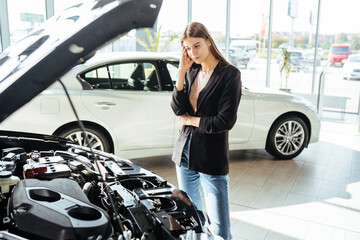 Wall Mural - Thoughtful woman choosing new car at modern showroom