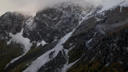 Wall Mural - Misty mountain landscape with fog over high peaks of the Alps and slopes covered in snow