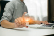 © aekachai - Businessman holding a bright light bulb saving bank a coins on wooden table