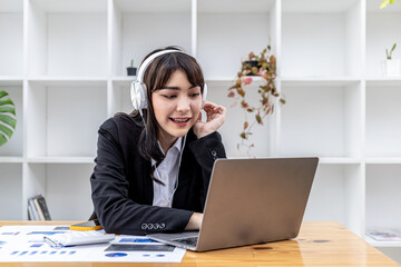 Businesswoman wearing headphones listening to music in her office, she is resting by listening to music, she gets emotional with the music and dances to the music. The relaxing idea at work.