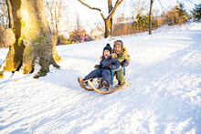Two Little Afro-american Or Latin Brothers In Warm Winter Clothes Sled Down The Snowy Mountain In Park Or Forest On Sunny Christmas Day. Having Fun, Excited, Laughing And Smiling. Childhood, Holidays