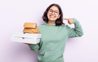 Wall Mural - pretty young woman smiling confidently pointing to own broad smile. fast food take away concept