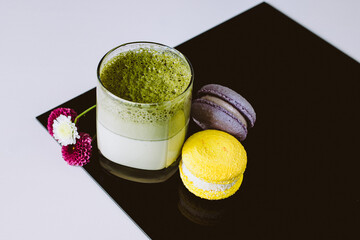 Wall Mural - matcha latte coffee in glass on blach white board with macaron and flowers