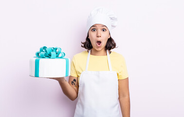 Wall Mural - pretty young woman looking very shocked or surprised. chef cooking a cake