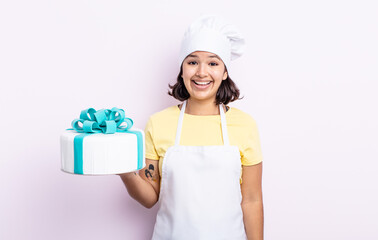 Wall Mural - pretty young woman looking happy and pleasantly surprised. chef cooking a cake