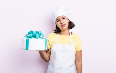 Wall Mural - pretty young woman feeling puzzled and confused. chef cooking a cake