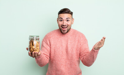 Wall Mural - young handsome man feeling happy and astonished at something unbelievable. cookies bottle concept