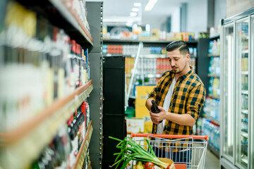 Wall Mural - Young handsome man in a supermarket grocery shopping