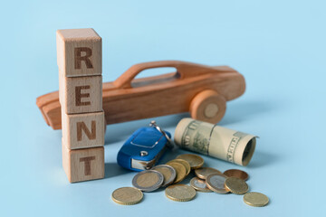 Wall Mural - Wooden car with word RENT, key and money on blue background