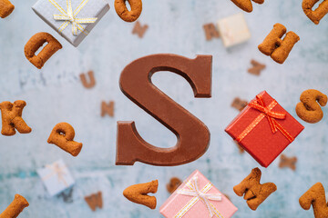 Dutch holiday Sinterklaas greeting Card. Gift boxes and traditional Saint Nicolas sweets falling or flying in motion or levitation. Pepernoten, chocolate letters. Concept children party five december.