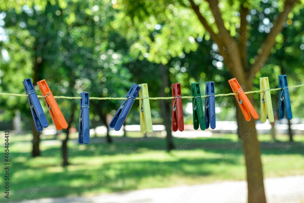 Many different clothespins hanging on laundry line outdoors