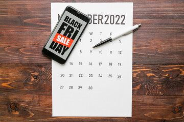 Poster - Mobile phone with text BLACK FRIDAY SALE, calendar and pen on dark wooden background