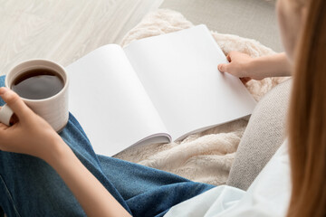 Canvas Print - Woman holding blank magazine and cup of tea on light background