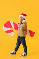 Sticker - Surprised little boy with candy cane pinata on color background