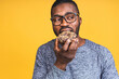 © denis_vermenko - Diet concept. Hungry african american black bearded man eating donut isolated over yellow background. Junk food.