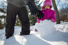 Father And Daughter Making A Snowball Together In Winter