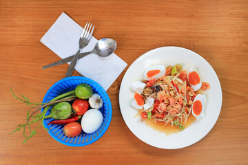 Wall Mural - Papaya Salad (Som Tam) with salt egg and shrimp the traditional Thai foods on wood table background. Most wanted popular food in Thailand. Top view.